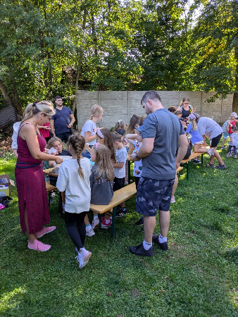 Děti soutěží ve skákání v pytlích během venkovní školní akce